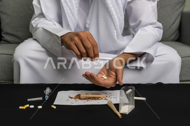Negative effects of addiction and abuse, taking toxic substances, engaging in harmful behavioral habits, suffering from psychological disorders and health problems, close-up image of the hands of an Arab Gulf Emirati man holding a group of narcotic pills