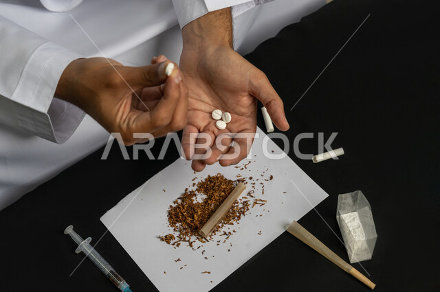 المعاناة من الاضطرابات النفسية والمشاكل الصحية، صورة مقربة لأيدي رجل عربي خليجي إماراتي يمسك  مجموعة من الحبوب مخدرة، الآثار السلبية للادمان والتعاطي، القيام بعادات سلوكية ضارة وتعاطي المواد السامة