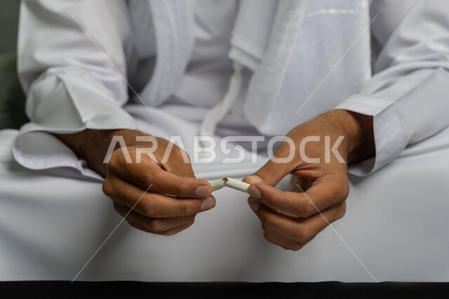 ايماءات تدل على الحذر من ادمان السجائر، محاربة عادة التدخين، التوقف عن اتباع العادات السلوكية الضارة وتعاطي المواد السامة، صورة مقربة لأيدي شاب عربي خليجي إماراتي يقوم بإتلاف لفافة تبغ