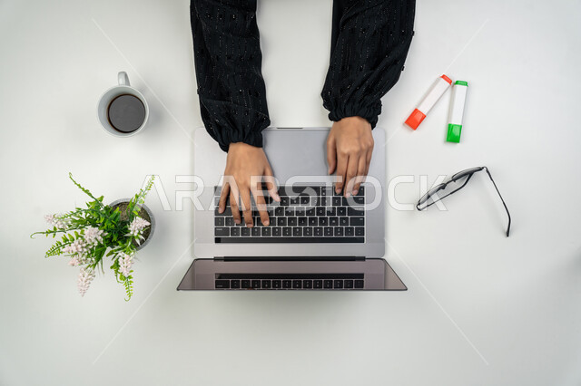 استخدام الأجهزة التقنية الحديثة في الأعمال المكتبية، انجاز مهام العمل عن بعد، بورتريه علوي عامودي ليدي امرأة عربية خليجية اماراتية تقوم بالكتابة على دفتر وبجانبها وأقلام ملونة ونظارات شمسية وكوب قهوة، سيدة سعودية تستخدم جهاز الحاسوب، خلفية بيضاء