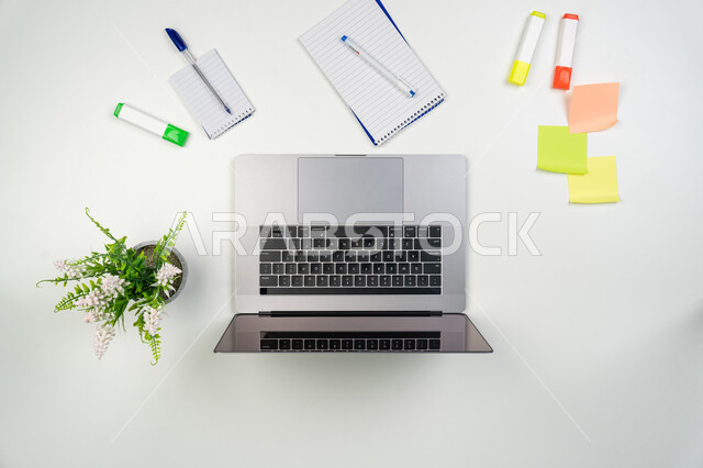 Notebooks, papers and colored pens, using modern and advanced technical devices in household chores, completing work tasks remotely, recording notes and writing down ideas, close-up image of a laptop and a set of stationery, white background