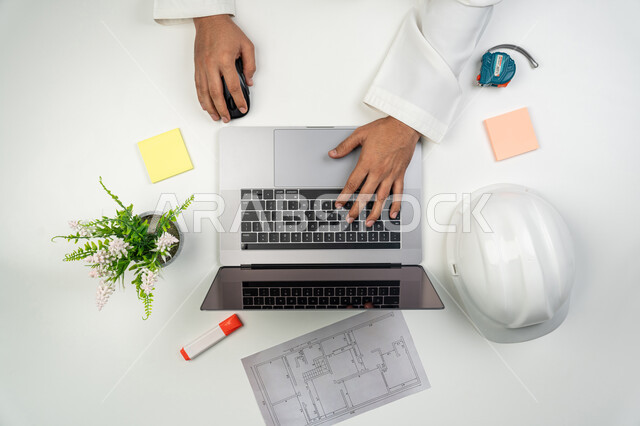 مهن و وظائف اختصاص الهندسة المعمارية, استخدام الأجهزة التقنية بالعمل, بورتريه علوي عامودي ليدين مهندس عربي خليجي إماراتي يقوم بإنجاز المهام على جهاز  الحاسوب, استخدام التكنولوجيا في الحياة العملية, خلفية بيضاء