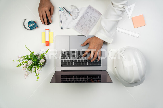 تطور و نمو القطاع الهندسي, الإشراف على المشاريع الهندسية، دمج التكنولوجيا الحديثة بالأعمال, بورتريه علوي عامودي ليدين مهندس عربي خليجي إماراتي يقوم بالكتابة على جهاز الحاسوب, استخدام التكنولوجيا في الحياة العملية, خلفية بيضاء