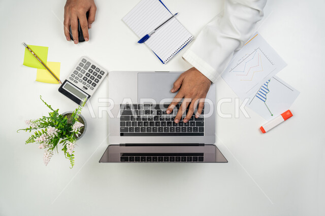 المتابعة و التخطيط للأعمال, دراسة الرسوم البيانية, مهن و أعمال مكتبية, بورتريه علوي عامودي ليدين رجل عربي خليجي إماراتي يقوم بالنقر على لوحة المفاتيح,  جمع بيانات البورصة و سوق الأسهم, خلفية بيضاء