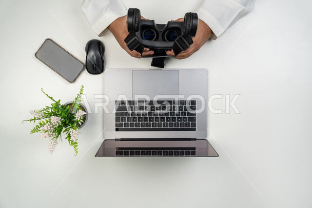 استخدام نظارات الواقع الافتراضي, العلوم والتكنولوجيا الحديثة والمتطورة, بورتريه علوي عامودي ليدين رجل عربي خليجي إماراتي يمسك بيديه نظارة الفي ار, خلفية بيضاء