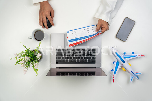 استخدام التقنيات الحديثة لإعداد الرحلات الترفيهية في أوقات الفراغ, بورتريه علوي عامودي ليدين رجل عربي خليجي إماراتي يمسك بيده وثيقة حجز, عمليات الحجز الالكتروني عبر جهاز الحاسوب المحمول, مفهوم السياحة و السفر, خلفية بيضاء