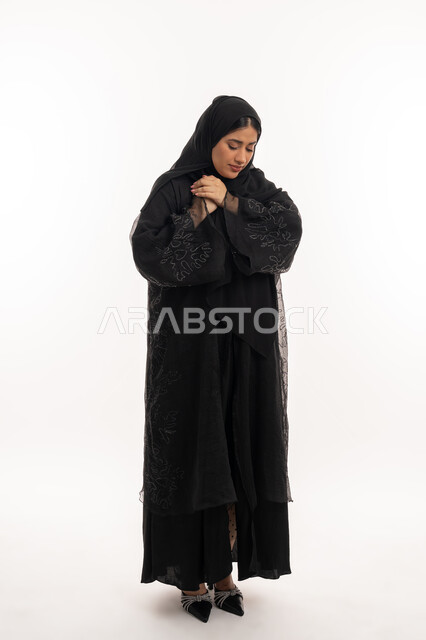 الذبحه الصدريه حالة مرضية، مشاكل صحية صعبة، إيماءات التعب والإرهاق والضغوطات النفسية، بورتريه لإمرأة عربية خليجية اماراتية محجبة ترتدي عباءة سوداء تضع يدها على قلبها تشعر بحالة سيئة من الوخز والألم، شابة سعودية مريضة، صورة لكامل الجسم، خلفية بيضاء