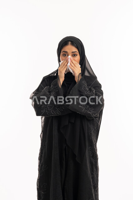 الإصابة بفايروس كورونا كوفيد19، الشعور بالتعب والمرض، استعمال المناديل الورقية أثناء العطس، بورتريه لامرأه عربيه خليجيه اماراتية محجبة ترتدي عباءة سوداء، إيماءات وجه ويدين تدل على العطاس، شابة سعودية مريضة، خلفية بيضاء