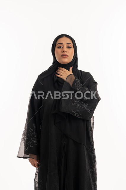 شابة سعودية مريضة، الشعور بالمرض والكحة، تعابير الالم والارهاق، الانفلونزا والتهاب الرئة، بورتريه لامرأة عربية خليجية اماراتية محجبة ترتدي عباءة سوداء تضع يدها حنجرتها بايماءات التوجع، خلفية بيضاء