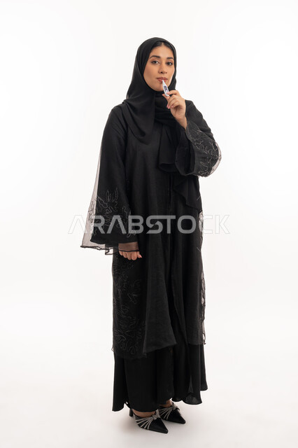 وضع خطة علاجية، الحاجة للمساعدة وزيارة الطبيب، الإصابة بالحمى والتعب، الإحساس بالمرض والإرهاق، بورتريه لامرأة عربية خليجية اماراتية محجبة ترتدي عباءة سوداء تقوم بقياس حرارتها باستخدام الميزان الرقمي، شابة سعودية مريضة، صورة لكامل الجسم، خلفية بيضاء