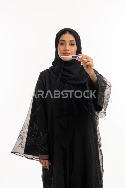 وضع خطة علاجية، الحاجة للمساعدة وزيارة الطبيب، الإصابة بالحمى والتعب، الإحساس بالمرض والإرهاق، بورتريه  لامرأة عربية خليجية اماراتية محجبة ترتدي عباءة سوداء تحمل بيدها الميزان الرقمي، شابة سعودية مريضة، خلفية بيضاء