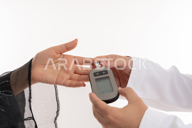 Modern electronic device for diabetes patients, medical conditions, problems and physical pains, health care and quick medical examination, close-up portrait of hand of Arab Gulf Emirati woman checking blood sugar, high blood sugar problems, sick young Saudi woman, white background