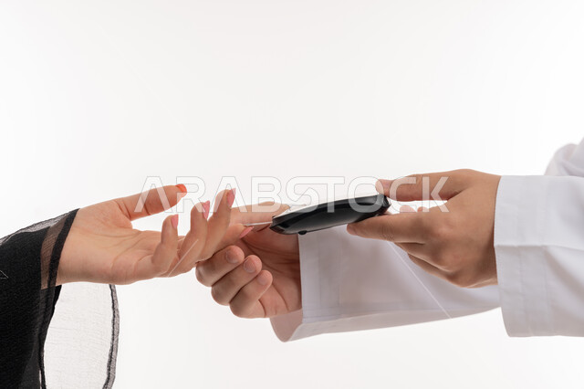 الرعاية الصحية والفحص الطبي السريع, حالات مرضية ومشاكل وآلام جسدية, جهاز إلكتروني حديث لمرضى داء السكري, بورتريه مقرب ليد امرأة عربية خليجية إماراتية تقوم بفحص نسبة السكر في الدم, مشاكل ارتفاع السكر في الدم, شابة سعودية مريضة، خلفية بيضاء