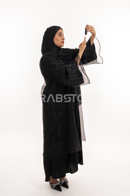 High blood sugar problems, modern electronic device for diabetics, medical conditions, problems and physical pains, health care and rapid medical examination, portrait of an Arab Gulf Emirati woman checking her blood sugar, a sick young Saudi woman, full body image, white background