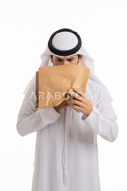 الشعور بضيق في النفس, المشاكل الصحية والحالات المرضية, بورتريه لرجل عربي خليجي إماراتي يرتدي الكندورة والغترة الاماراتية يحمل كيس ورقي يساعد على الاحتفاظ بهواء الزفير والتنفس في حالة الهلع, خلفية بيضاء