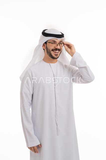 الشعور بالسعادة والفرح بوضوح الرؤية, استخدام النظارة الطبية لتصحيح البصر, مفهوم طول النظر وقصره, بورتريه لرجل عربي خليجي اماراتي يرتدي الكندورة والغترة يضع يديه على نظاراته بإيماءات البشاشة, خلفية بيضاء