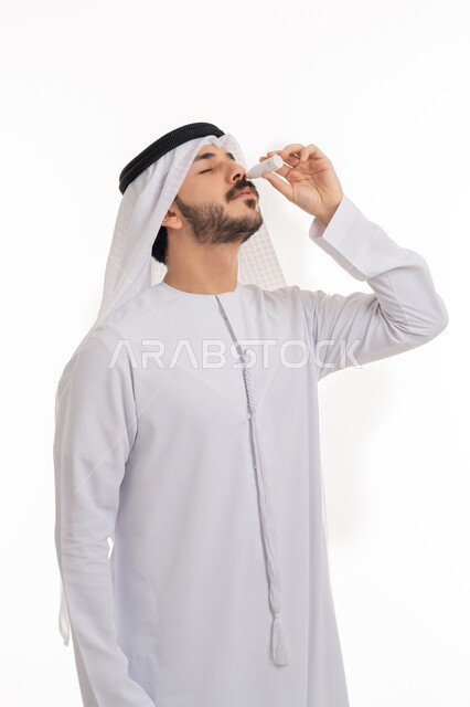 الاحساس بالحرقة و احمرار العيون، ارتفاع ضغط العين، الحاجة للفحص وعلاج حالات التهاب العصب البصري، بورتريه لرجل عربي خليجي اماراتي يرتدي الكندورة والغترة يقوم بوضع قطرة عينية, خلفية بيضاء