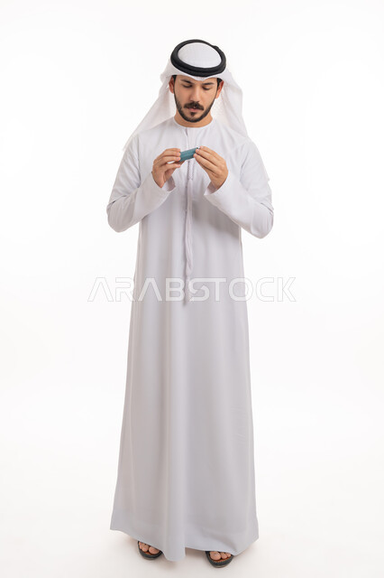 قراءة صلاحية المنتج والتركيبة الدوائية,  المحافظة على ممر هوائي منتظم، مشاكل في الجهاز التنفسي، بورتريه لرجل عربي خليجي اماراتي يرتدي الكندورة والغترة يحمل بيده جهاز الرذاذ الخاص بمرض الربو، أجهزة استنشاق المخصصة للمرضى، صورة الجسم بالطول الكامل, خلفية بيضاء