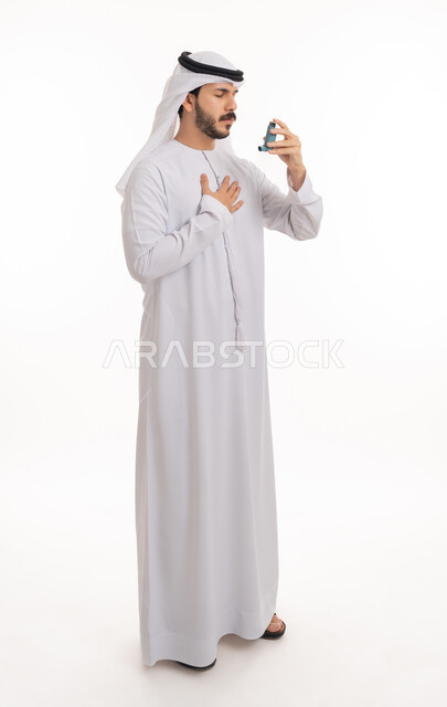 أجهزة استنشاق المخصصة للمرضى، مشاكل في الجهاز التنفسي، بورتريه لرجل عربي خليجي إماراتي يرتدي الكندورة والغترة يحمل بيده جهاز الرذاذ الخاص بمرض الربو، المحافظة على ممر هوائي منتظم, صورة الجسم بالطول الكامل, خلفية بيضاء