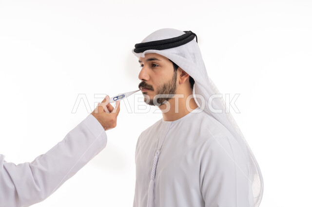 اتباع إجراءات السلامة والوقاية، الإحساس بالمرض والإرهاق، الحاجة للمساعدة وزيارة الطبيب، الإصابة بالحمى والتعب, بورتريه مقرب من الجانب لرجل عربي خليجي إماراتي يرتدي الكندورة والغترة الاماراتية يقوم بقياس درجة حرارته باستخدام الميزان الرقمي, خلفية بيضاء