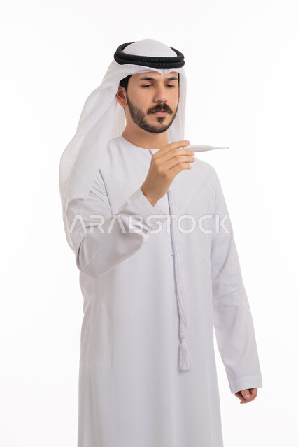 ضرورة زيارة الطبيب لوضع الخطة العلاجية، مفهوم الاهتمام بالصحة الجسدية, الإحساس بالمرض والإرهاق، بورتريه لشاب عربي خليجي إماراتي يرتدي الكندورة والغترة ينظر إلى مؤشر الميزان الرقمي بتعابير الانزعاج والتعب، خلفية بيضاء