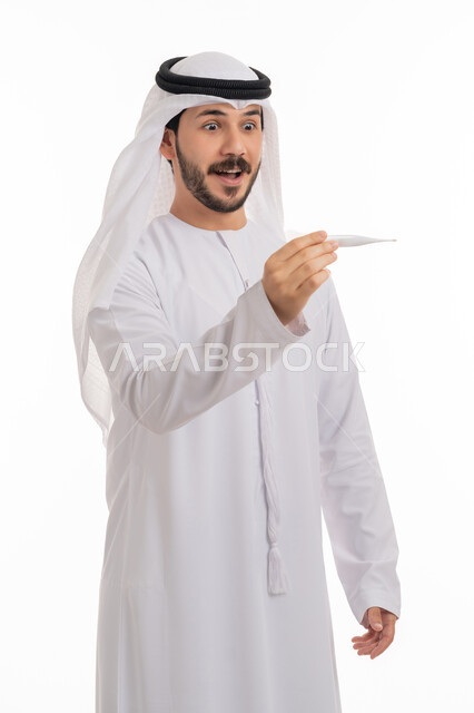 اتباع اجراءات السلامة والمحافظة على الصحة الجسدية, الوقوف بإيماءات الدهشة والاستغراب والذهول, بورتريه لرجل عربي خليجي اماراتي يرتدي الكندورة والغترة ينظر إلى مؤشر الميزان الرقمي لقياس الحرارة, خلفية بيضاء