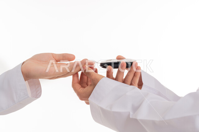 الأمراض الجسدية والحالات المرضية المزعجة, الإصابة بداء السكري، بورتريه ليدين شاب عربي خليجي اماراتي مريض يرتدي الكندورة يقوم بفحص نسبة السكر في دمه، أجهزة الكترونية حديثة للفحص الطبي السريع, خلفية بيضاء