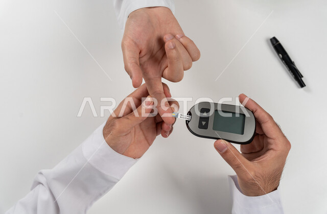 Physical pain and medical conditions, problems with high blood sugar, a vertical overhead portrait of an Arab Gulf Emirati man checking his blood sugar level, health care and rapid medical examination, modern electronic devices for diabetes patients, white background