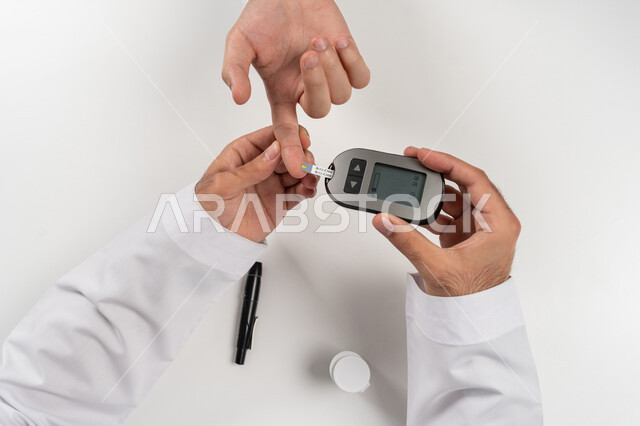 مشاكل ارتفاع السكر في الدم, بورتريه مقرب علوي عامودي لرجل عربي خليجي اماراتي يقوم بفحص نسبة السكر في الدم, الرعاية الصحية والفحص الطبي السريع, الأجهزة الالكترونية الحديثة لمرضى داء السكري, الالام الجسدية والحالات المرضية, خلفية بيضاء