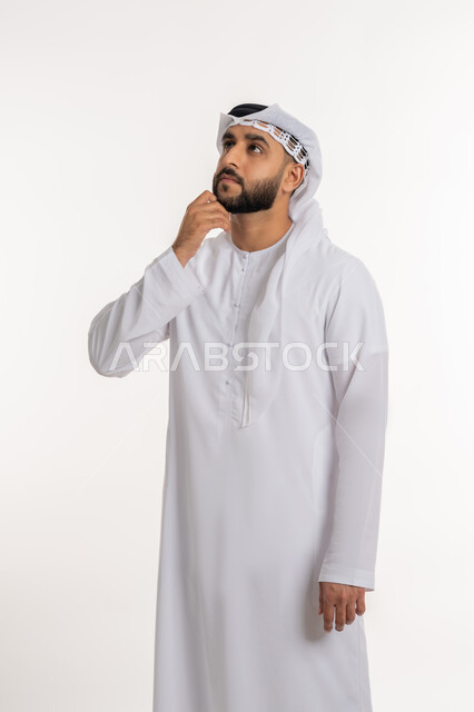 التأمل و التخطيط للمستقبل، التمعن والتركيز لإيجاد حل لمشكلة، بورتريه لرجل عربي خليجي اماراتي يرتدي الكندورة والغترة يضع يده على ذقنه بإيماءات التفكير بشيء ما, خلفية بيضاء