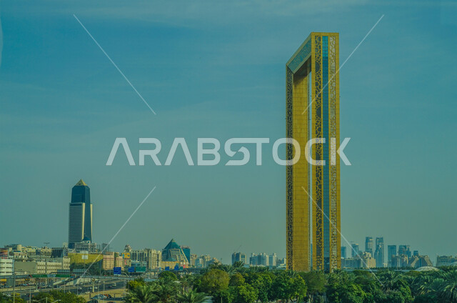 الفن الهندسي المعماري لبرواز مدينة دبي، النمو والتطور العمراني في الامارات، مبنى زجاجي بالوان ذهبية، اشجار النخيل الخضراء في وضح النهار، معالم واماكن سياحية مشهورة في دبي