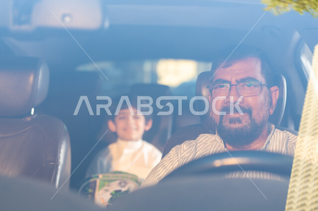 مفهوم القيادة والتوصيل الآمن، مهن ووظائف سعودية، استقدام العمالة من الخارج، سائق باكستاني مبتسم يرتدي النظارة الطبية يقوم بنقل طفل عربي خليجي سعودي بإيماءات الفرح والسرور