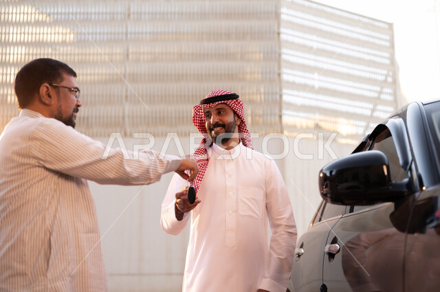 وظائف ومهن سعودية، استقدام العمالة من الخارج، سائق باكستاني يرتدي النظارة الطبية يقوم بإعادة مفتاح السيارة لرجل عربي سعودي خليجي يرتدي الشماغ والثوب التقليدي بإيماءات السرور، مفهوم القيادة والتوصيل، نهاية دوام العمل