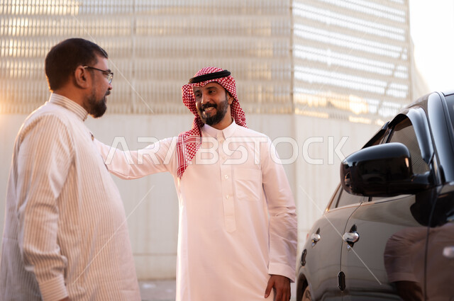 وظائف ومهن سعودية، استقدام العمالة من الخارج، رجل عربي سعودي خليجي يرتدي الشماغ والثوب التقليدي يتحادث مع السائق الباكستاني بإيماءات السرور، مفهوم القيادة والتوصيل، نهاية دوام العمل