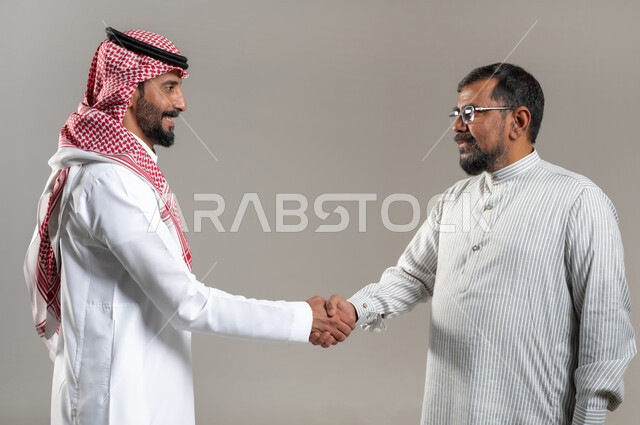استقدام العمالة من الخارج, الاتفاق على عقد صفقة عمل جديدة, بورتريه مقرب لرجل يرتدي الزي الباكستاني و النظارات الطبية يقوم بمصافحة رجل سعودي يرتدي الثوب و الشماغ التقليدي ,خلفية رمادية