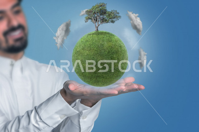 Close-up of the hand of a Saudi Gulf man with a green globe and tree on it, World Earth Day, Preserving the environment and the planet for the future, Increasing the green layer on Earth, spreading awareness to reduce environmental pollution, Green Saudi 