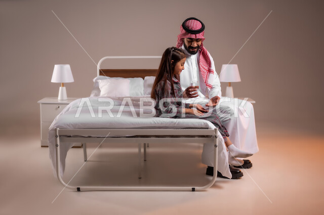 المحافظة على سلامة الجهاز المناعي للجسم، الاهتمام بصحة الابناء، المداومة على شرب المياه، الشعور بالعطش والجفاف، بورتريه مقرب لأب عربي خليجي سعودي يجلس على السرير يقوم بتقديم كوب ماء زجاجي لابنته، خلفية ملونة