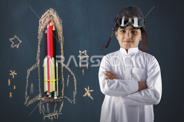 طفل خليجي سعودي مكتف اليدين، بتعبيرات وجه مختلفة ، يتمتع بصحة عقلية سلمية ، الثقة بالنفس ،استخدام الرسم لتعزيز الخيال والتعبير عن الافكار  ، خلفية صاروخ مرسوم والوان 