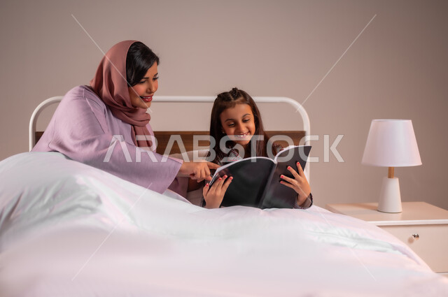 المشاركه بقراءه القصص المفيده مع الأبناء قبل النوم، مفهوم التربيه القائمه على الحب والحنان، بورتريه لامرأة عربية خليجية سعودية تقرأ الروايات المسليه لابنتها، قضاء وقت ممتع مع الأبنه قبل النوم، خلفية ملونة