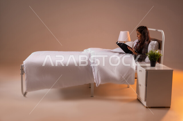 قراءة الروايات والقصص الممتعة، الشعور بالراحة والطمأنينة, بورتريه لبنت عربية خليجية سعودية مبتسمة تجلس في سرير مريح تمسك بيدها الكتاب، الاسترخاء والاستمتاع بالأجواء الهادئة، اتباع أسلوب حياة صحي، خلفية ملونة