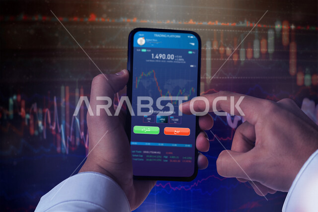 صورة مقربة لرجل عربي سعودي خليجي يحمل بيديه الموبايل و يتابع صعود و نزول البورصة والاسهم المالية .