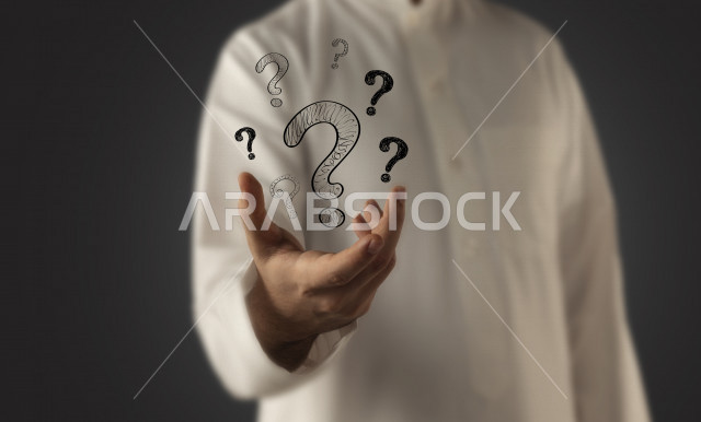 صورة مقربة لرجل عربي سعودي خليجي ، مع مجموعة من اشكال الاستفهامات المتناثرة فوق يديه ، تساؤلات و استفسارات ، ايماءات وتعابير جسدية .