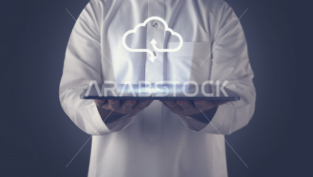 صورة مقربة لرجل عربي  سعودي خليجي يحمل بيده جهاز تقني ذكي عليه سحابة الكترونية بتقنية الهولوجرام ، ثلاثية الابعاد ، السحابة الالكترونية .