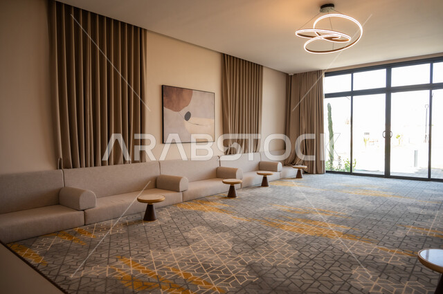 نوافذ وواجهات زجاجية المطلة على الحديقة الخارجية، الديكورات الداخلية الراقية للفلل والشقق السكنية في المملكة العربية السعودية، غرفة معيشة مع أثاث منزلي فاخر باللون البيج، التصاميم الداخلية لغرف الجلوس المريحة على الطراز الحديث