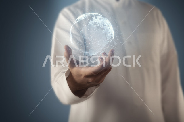 A close-up image of an Arab, Saudi, and Gulf man holding a stereoscopic, miniature globe with 3D hologram technology, innovation, technological creativity.