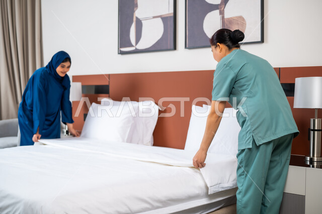 استقدام العمالة الاجنبية المدربة من الخارج، القيام بالمهام والأعمال الروتينية، عاملة فلبينية ترتدي اليونيفورم الخاص بالعمل تقوم بترتيب السرير في غرفة النوم، إمرأة عربية خليجية سعودية تقوم بإعطاء التعليمات التوجيهات للخادمة، توفيرخدمات العناية وترتيب المنزل