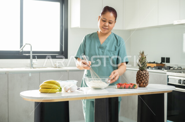 Preparing and preparing desserts, preparing delicious sweets in the kitchen, a worker wearing a special uniform mixing ingredients and amounts, employing licensed and qualified workers from Saudi companies and offices, hiring a foreign maid for domestic services.