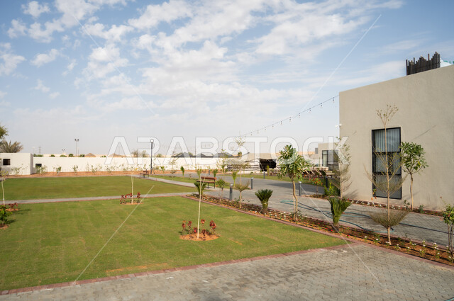 Trees and green plants surrounding tourist residential apartments and villas, urban growth and progress in the Kingdom of Saudi Arabia, modern architectural art, distinct modern designs for the outdoor garden, luxurious designs and decorations.
