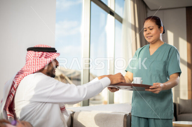 الخادمات في البيوت السعودية، القيام بالمهام والأعمال المنزلية الروتينية، المعاملة الحسنة للخادمة الاجنبية، مهن ووظائف نسائية, سيد عربي خليجي سعودي مع عاملة فلبينية ترتدي اليونيفورم الخاص بالعمل تقوم بتقديم القهوة، حسن الضيافة والاستقبال