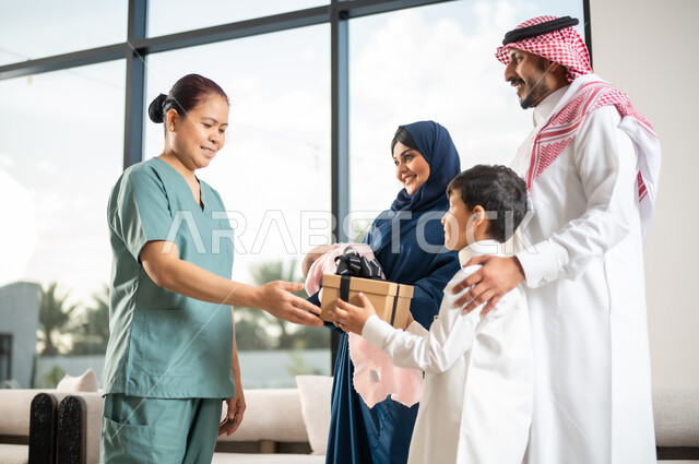 مهن ووظائف نسائية، استقدام العمالة الخارجية المرخصة والمؤهلة، أجواء عائلية سعيدة مليئة بالتقدير والاحترام، طفل عربي سعودي خليجي يقوم بتقديم علبة هدية لخادمة فلبينية لجودة خدمتها وأدائها، الإحسان في التعامل مع الخادمات في البيوت في السعودية